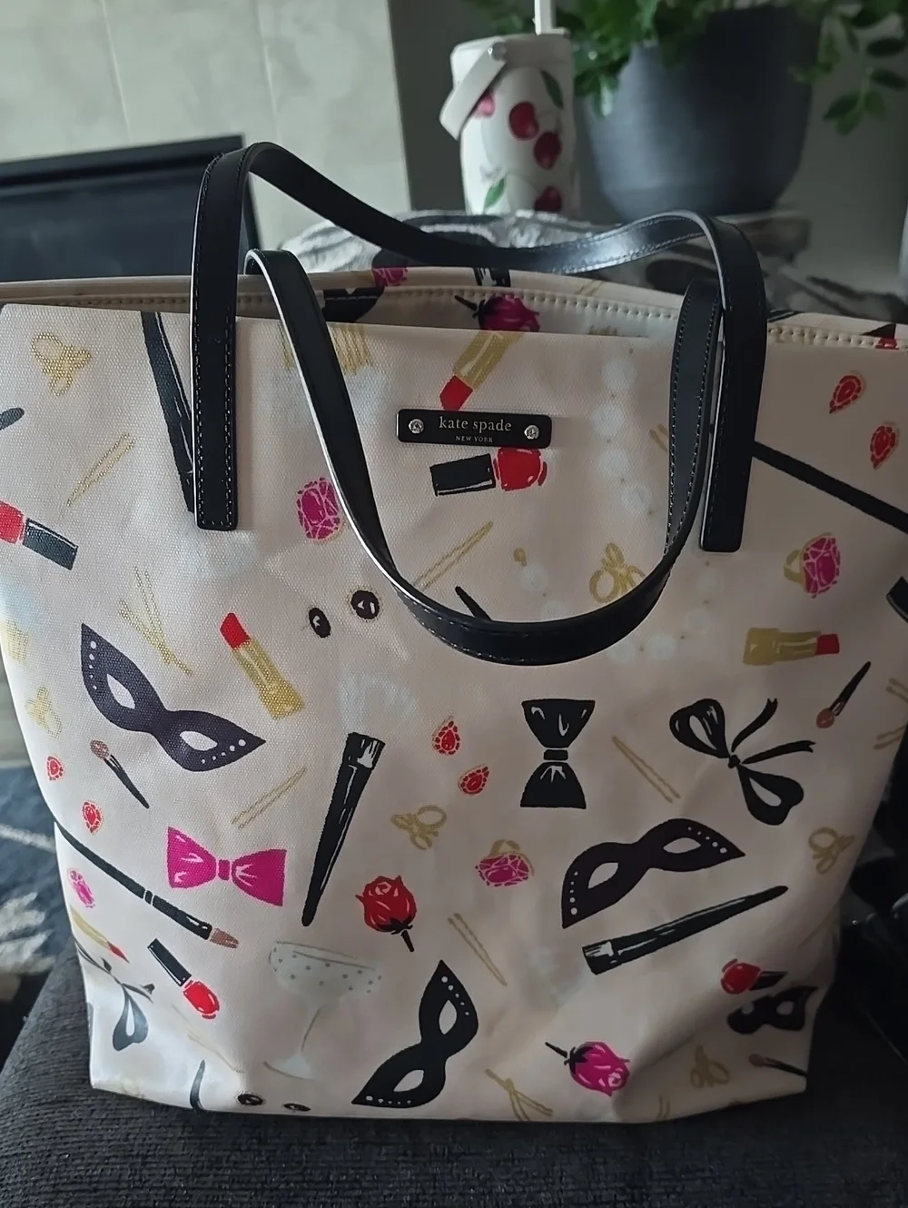 kate spade cream tote with black handles and colorful makeup print